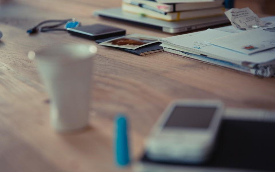 Mesa de escritório com envelopes, cartas, cadernos e um celular